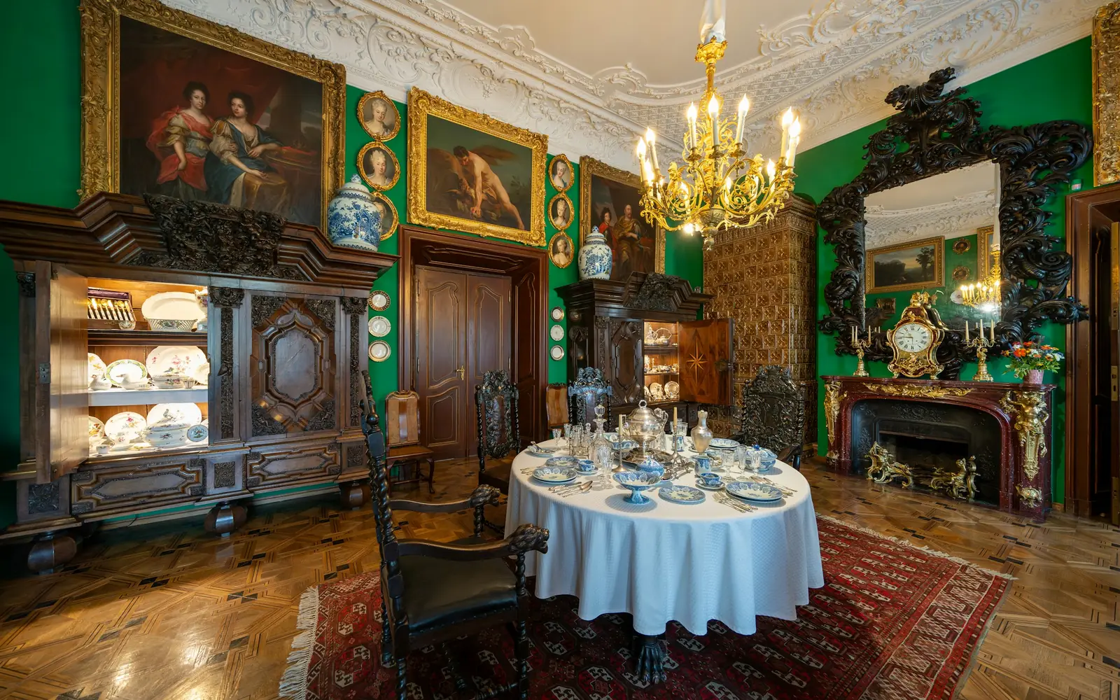 A dining room inside Wawel Castle with green walls, a chandelier and a laid table