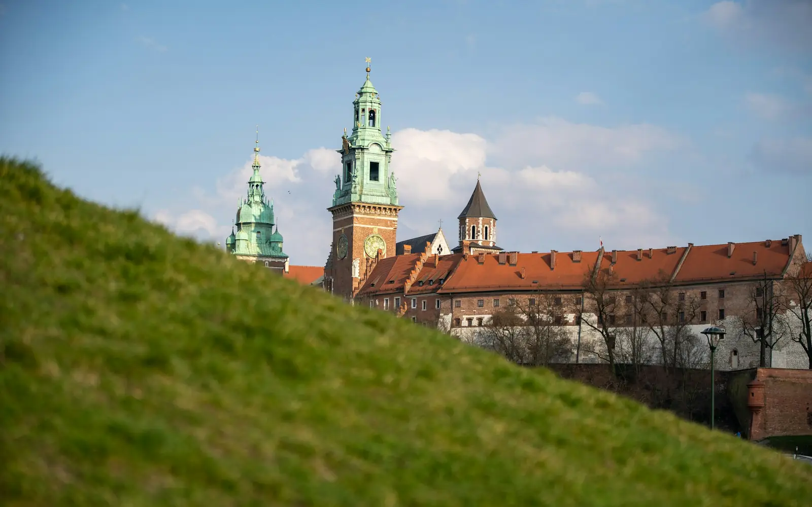 Wawel Royal Castle on its limestone hill above the Vistula, red-brick towers and the cathedral dome against the sky